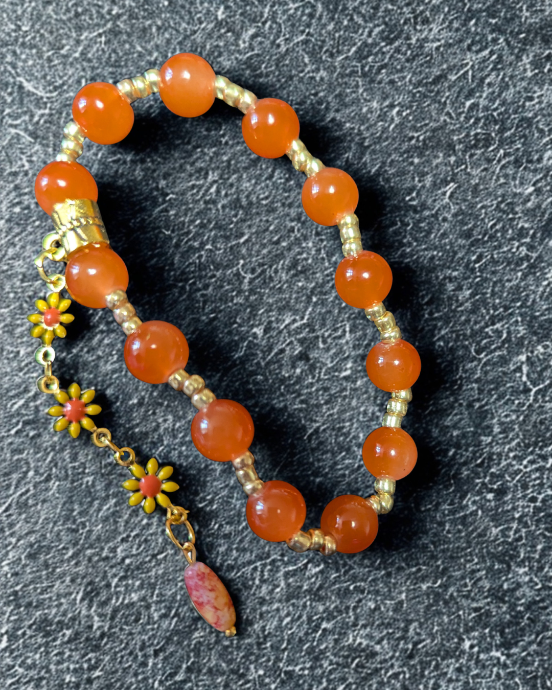 Pulsera elástica artesanal con cuentas naranjas y dije floral