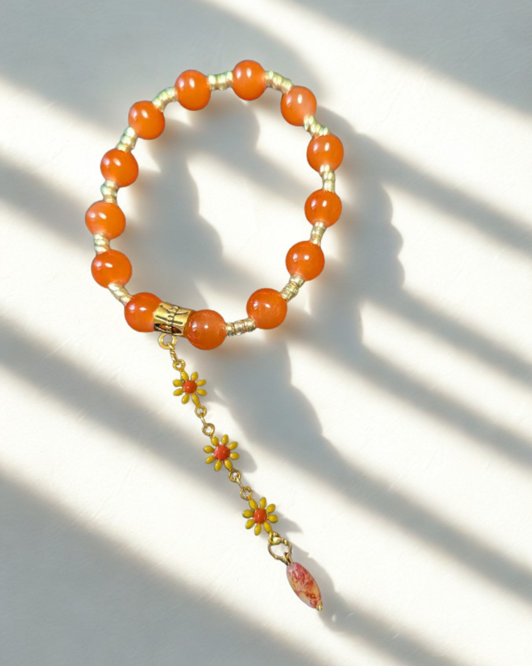 Pulsera elástica artesanal con cuentas naranjas y dije floral